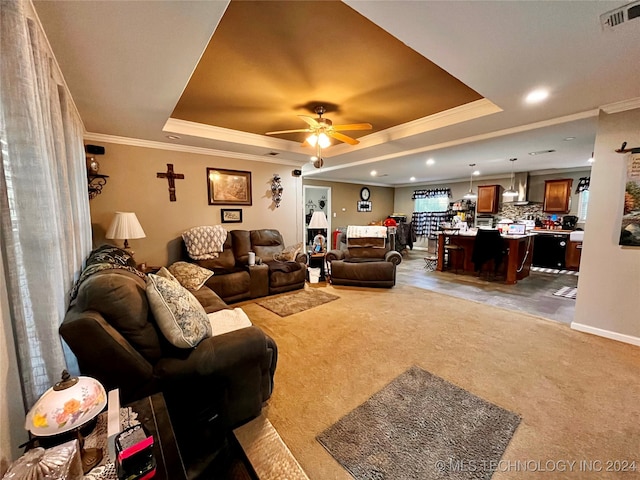 living room with carpet flooring, a raised ceiling, ceiling fan, and crown molding