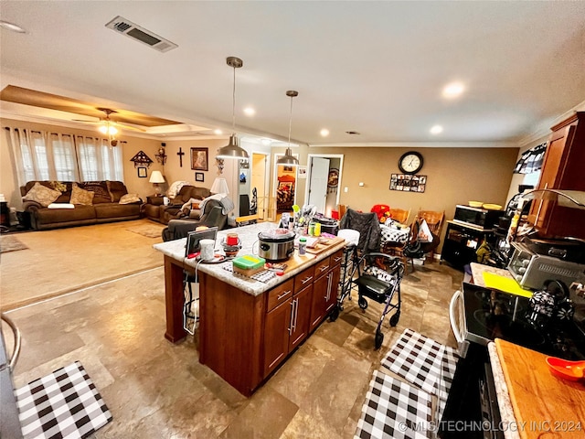 kitchen with ceiling fan, a kitchen island, decorative light fixtures, and ornamental molding