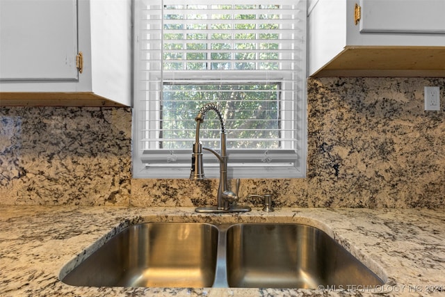 details with white cabinets, sink, and tasteful backsplash