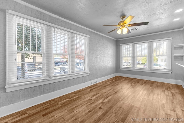 spare room featuring wood-type flooring, ornamental molding, ceiling fan, and a healthy amount of sunlight