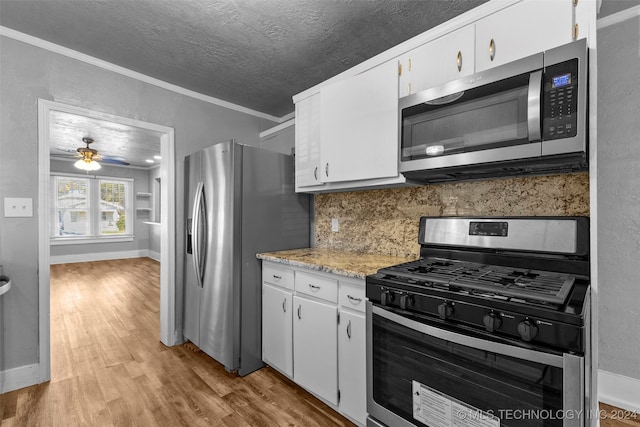 kitchen featuring white cabinetry, ornamental molding, appliances with stainless steel finishes, and light hardwood / wood-style flooring