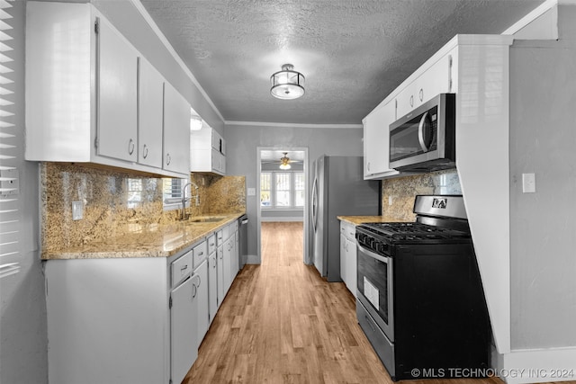 kitchen featuring white cabinetry, sink, stainless steel appliances, tasteful backsplash, and light hardwood / wood-style flooring