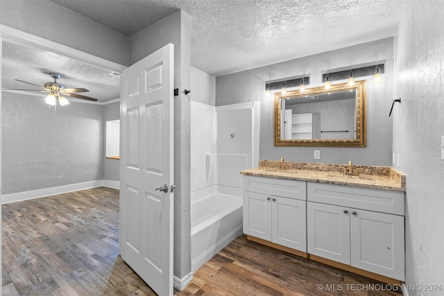 bathroom featuring hardwood / wood-style floors, ceiling fan, shower / bathtub combination, and a textured ceiling