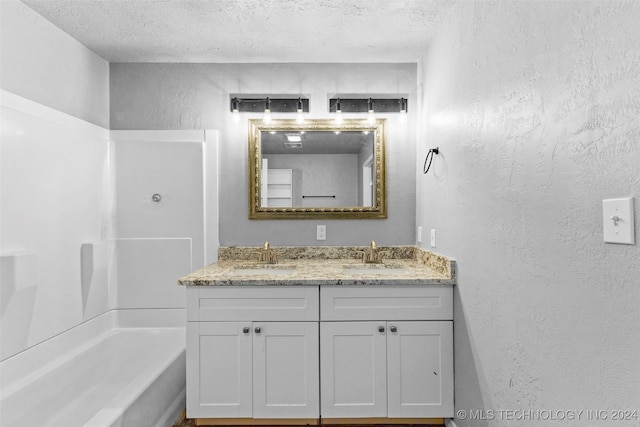 bathroom featuring vanity, a tub to relax in, and a textured ceiling