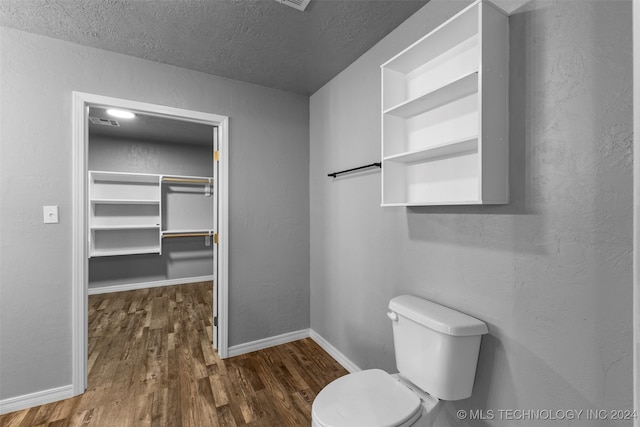 bathroom with toilet, a textured ceiling, and hardwood / wood-style flooring