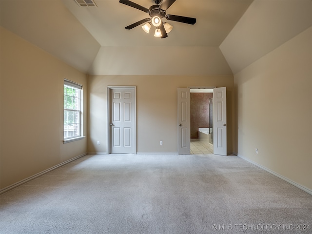 unfurnished bedroom with ceiling fan, ensuite bath, light carpet, and vaulted ceiling