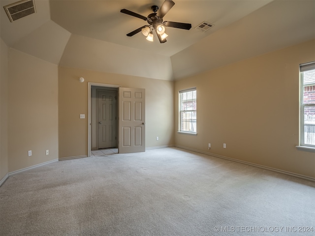 spare room with ceiling fan, a healthy amount of sunlight, light colored carpet, and vaulted ceiling