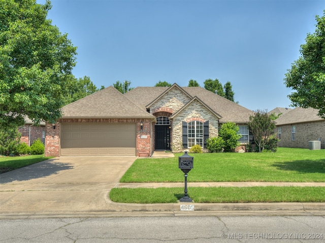 view of front facade with a garage, central AC unit, and a front yard