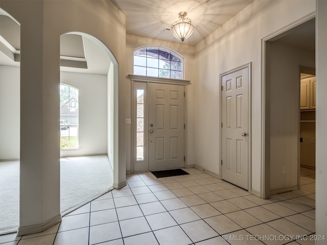 carpeted entrance foyer with plenty of natural light and a notable chandelier