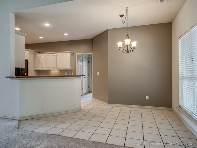 kitchen featuring white cabinetry, kitchen peninsula, pendant lighting, a chandelier, and fridge