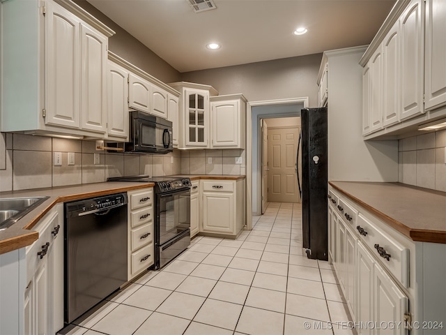 kitchen with black appliances, white cabinets, light tile patterned floors, and tasteful backsplash