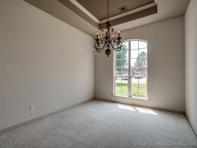 carpeted spare room with a raised ceiling, ornamental molding, a healthy amount of sunlight, and a notable chandelier