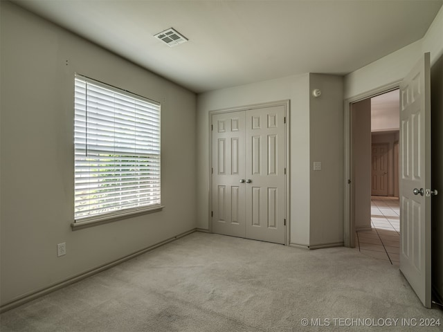 unfurnished bedroom featuring light carpet and a closet