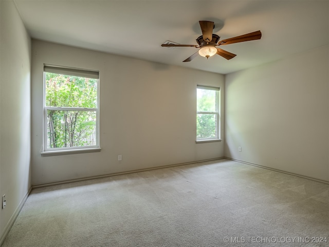 empty room with ceiling fan, a healthy amount of sunlight, and light carpet