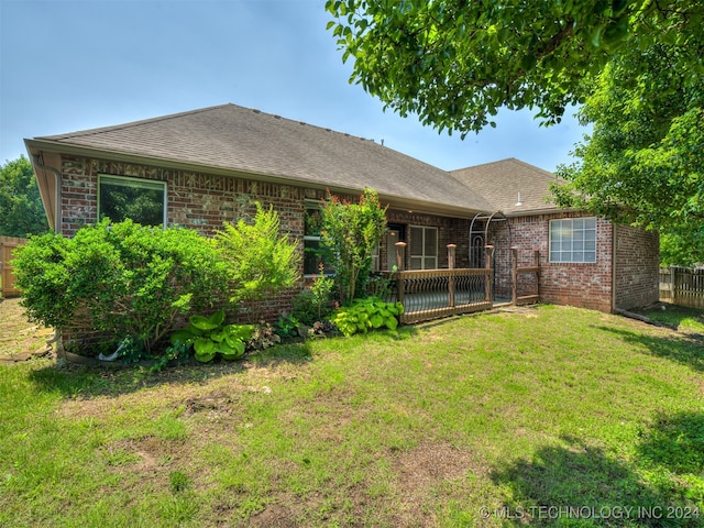 rear view of house with a deck and a lawn