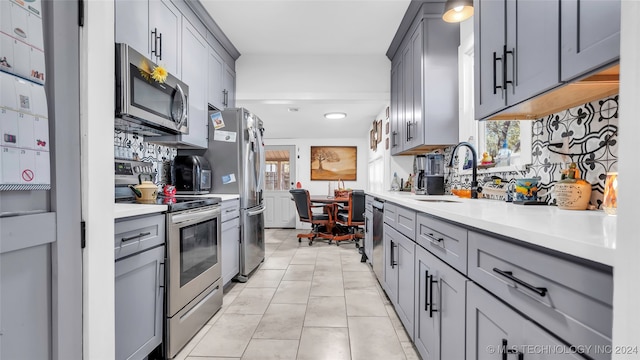 kitchen featuring gray cabinets, a healthy amount of sunlight, light tile patterned floors, and stainless steel appliances