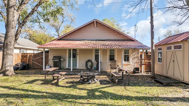 back of property featuring a fire pit, a shed, and a lawn