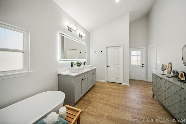 bathroom featuring a bathing tub, vanity, wood-type flooring, and high vaulted ceiling