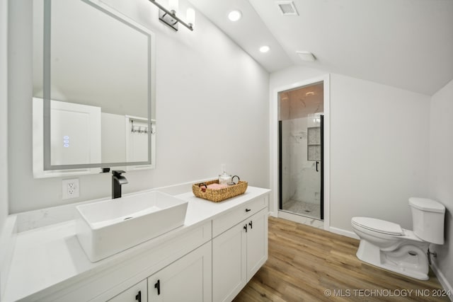 bathroom with vanity, a shower with door, vaulted ceiling, hardwood / wood-style flooring, and toilet