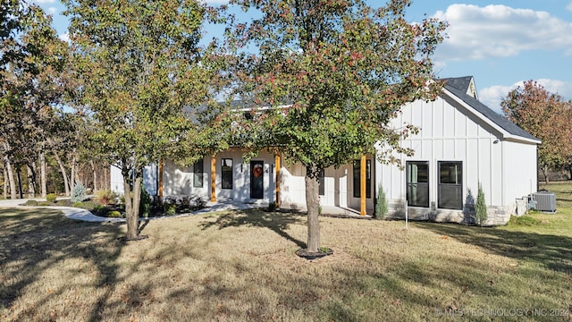 view of front of home featuring cooling unit and a front yard