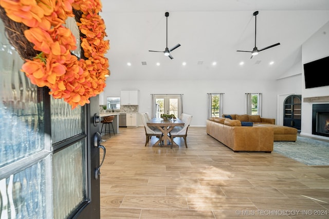 living room featuring ceiling fan, light hardwood / wood-style flooring, high vaulted ceiling, and french doors