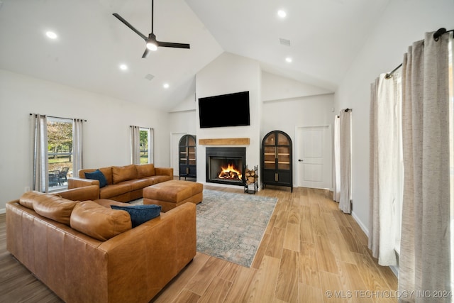 living room featuring ceiling fan, high vaulted ceiling, and light hardwood / wood-style flooring