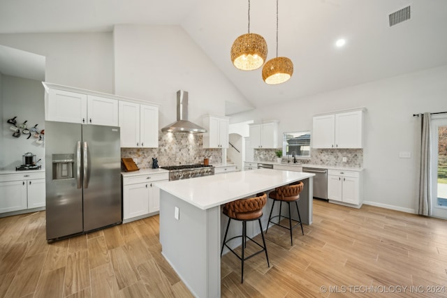 kitchen featuring white cabinetry, a healthy amount of sunlight, wall chimney range hood, and appliances with stainless steel finishes