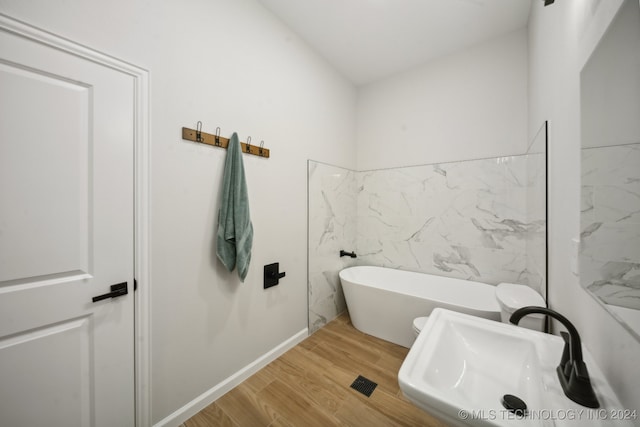 bathroom featuring wood-type flooring, tile walls, a bathtub, and sink