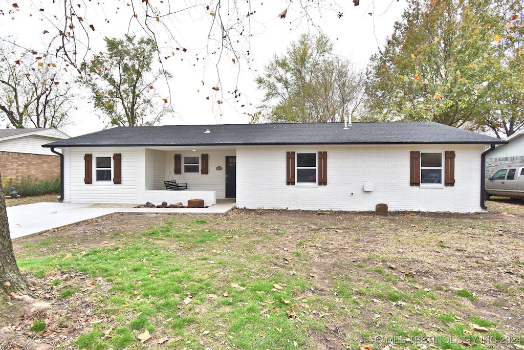 ranch-style home with a front lawn and a patio area