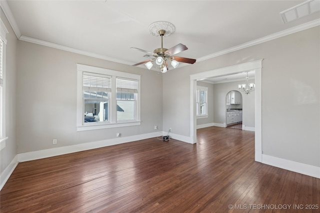 spare room featuring dark wood-type flooring, ornamental molding, ceiling fan with notable chandelier, and plenty of natural light