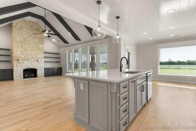 17537 S 56th E Ave, Bixby, OK 74008 - kitchen featuring a sink, light countertops, light wood-style flooring, a fireplace, and a center island with sink