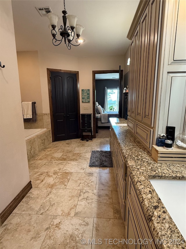 bathroom with a chandelier, vanity, and tiled tub