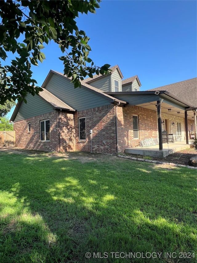 back of property with a lawn and a patio