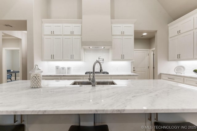 2708 W Van Buren Ct, Broken Arrow, OK 74134 - kitchen with a breakfast bar, backsplash, white cabinets, light stone counters, and vaulted ceiling