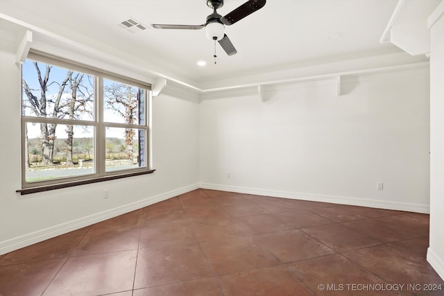 spare room with ceiling fan and dark tile patterned floors