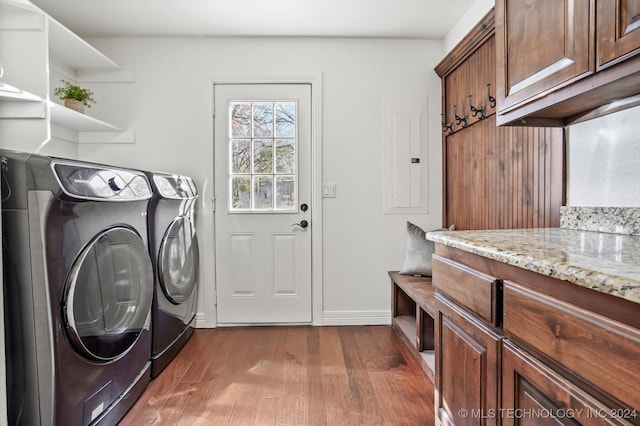 clothes washing area featuring washing machine and clothes dryer, electric panel, dark hardwood / wood-style flooring, and cabinets