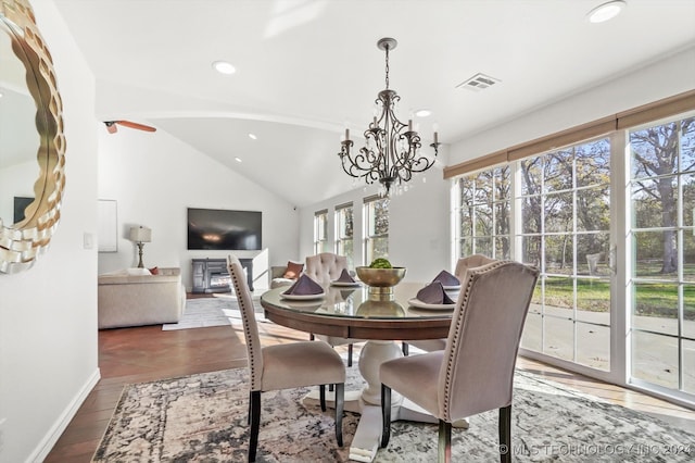 dining space with dark hardwood / wood-style flooring, lofted ceiling, a wealth of natural light, and an inviting chandelier