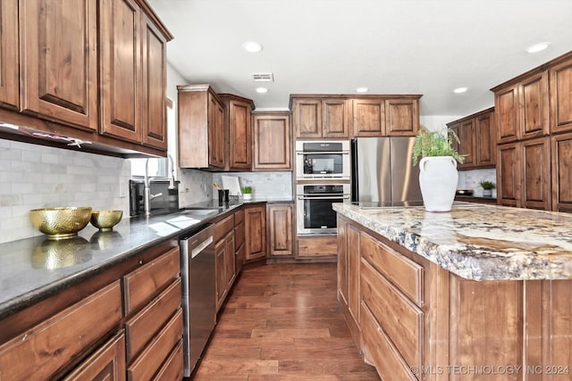 kitchen featuring decorative backsplash, dark stone counters, stainless steel appliances, and dark wood-type flooring