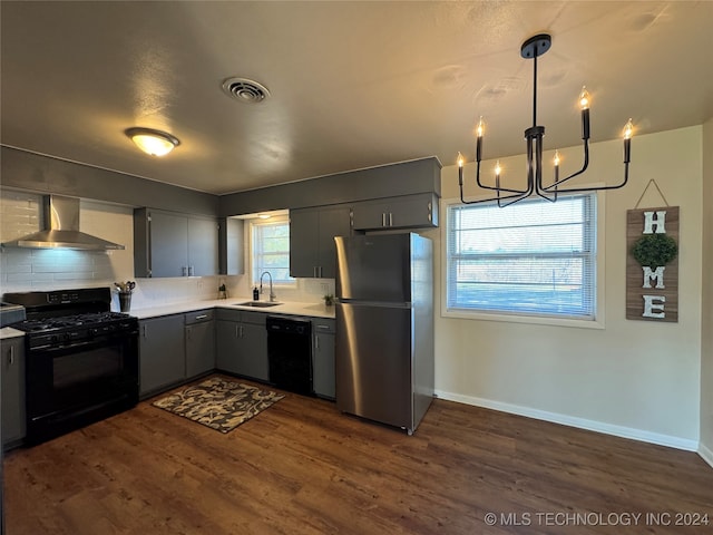 kitchen with wall chimney exhaust hood, dark wood-type flooring, sink, black appliances, and hanging light fixtures