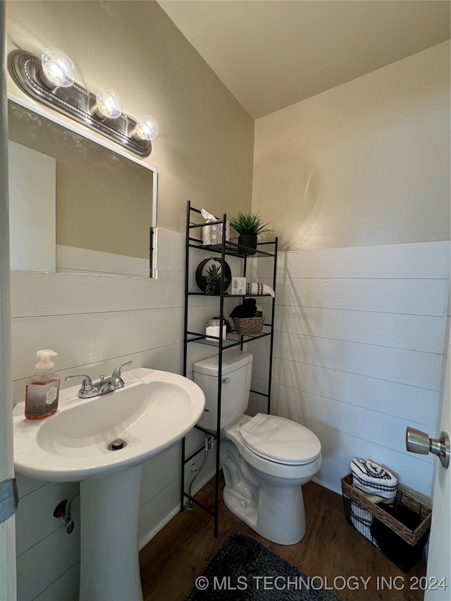 bathroom with hardwood / wood-style floors, toilet, and tile walls