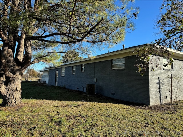 view of side of property featuring central AC unit and a lawn