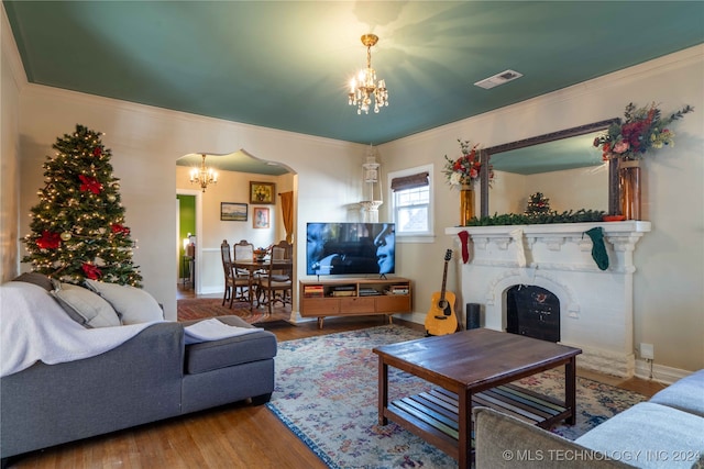 living room featuring wood-type flooring, crown molding, and an inviting chandelier