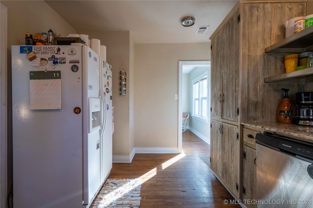 kitchen with light stone counters, dishwasher, hardwood / wood-style floors, and white refrigerator with ice dispenser