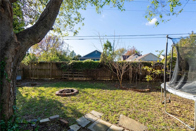 view of yard with an outdoor fire pit and a trampoline