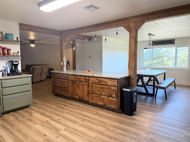 kitchen featuring light hardwood / wood-style flooring, ceiling fan, a textured ceiling, decorative light fixtures, and light stone counters