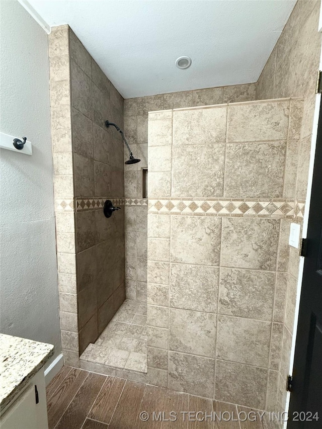 bathroom with tiled shower and vanity