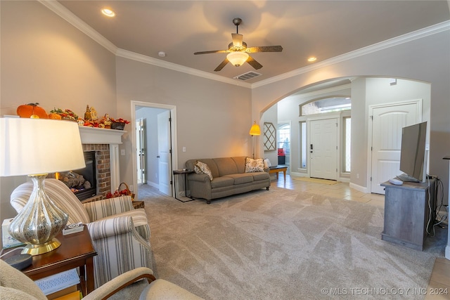 living area with visible vents, arched walkways, ceiling fan, light carpet, and crown molding