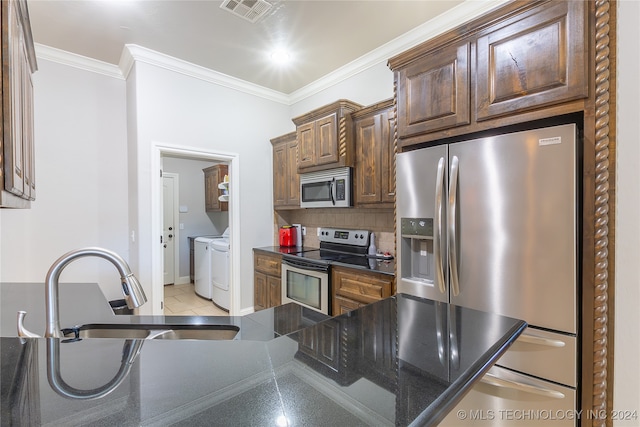 kitchen featuring sink, stainless steel appliances, separate washer and dryer, backsplash, and light tile patterned floors