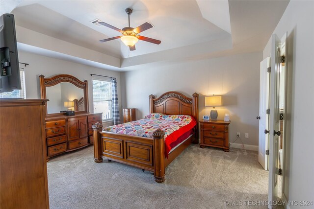 bedroom featuring ceiling fan, a raised ceiling, and light colored carpet