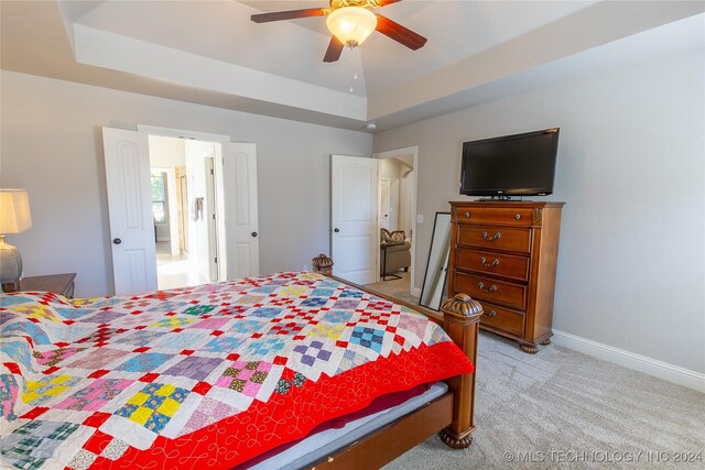 bedroom with light colored carpet, a raised ceiling, and ceiling fan